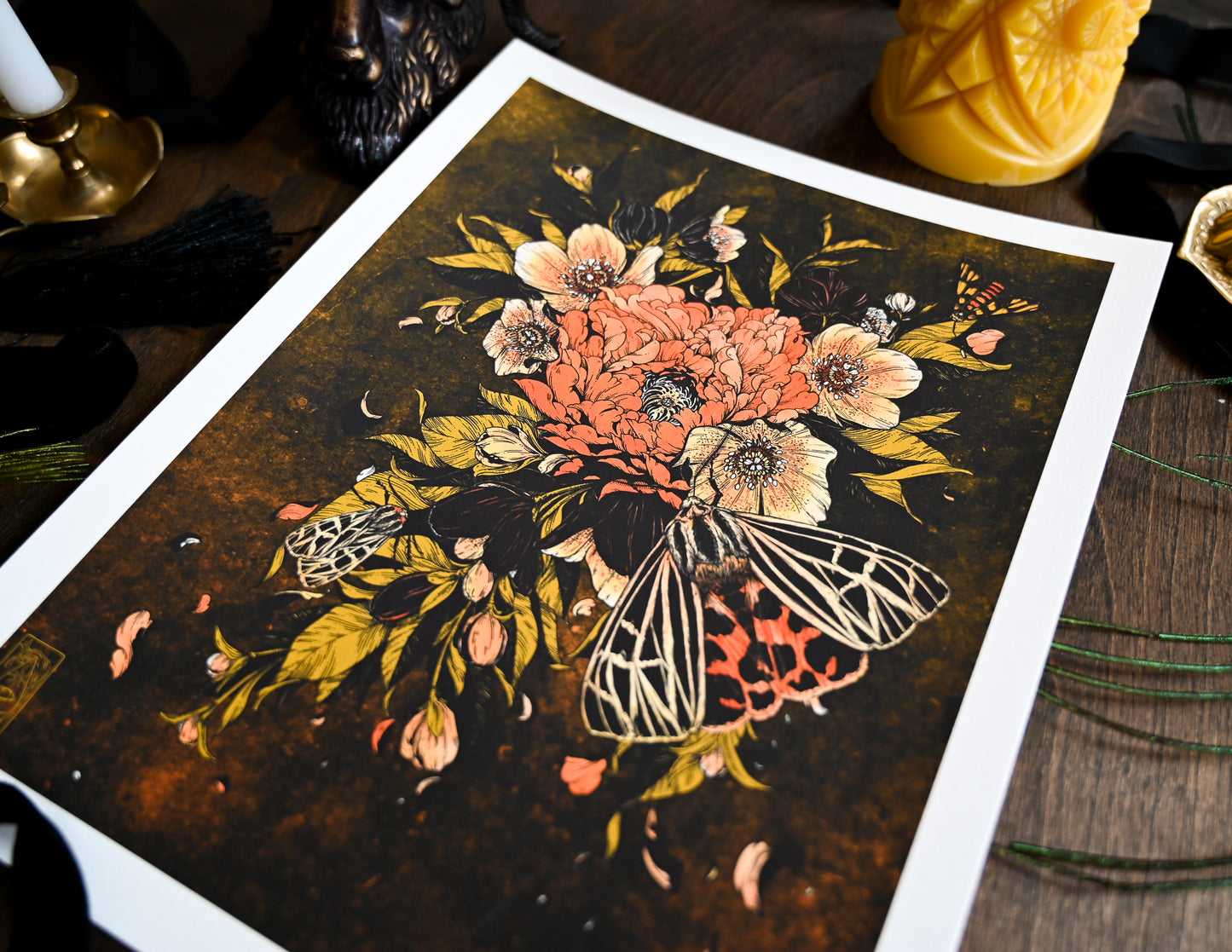 An up close of the print Bloom Lepis. The photo is looking at the print of from left to right. It shows The textured back ground of the print that is black and orange. It shows the details on the flowers and on the largest of the three moths. ow how detai;ed
