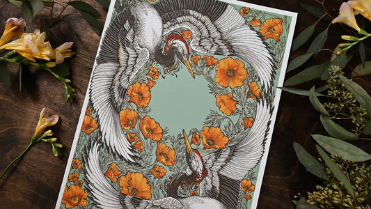 An up close photo showing the print at a diagonal from left to right. You can clearly see the center of the print. The cranes and poppies create space for an empty circle. There are fresh flowers on the table. 